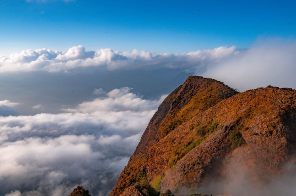 Stunning view of a mountain peak rising above the clouds under a clear blue sky.